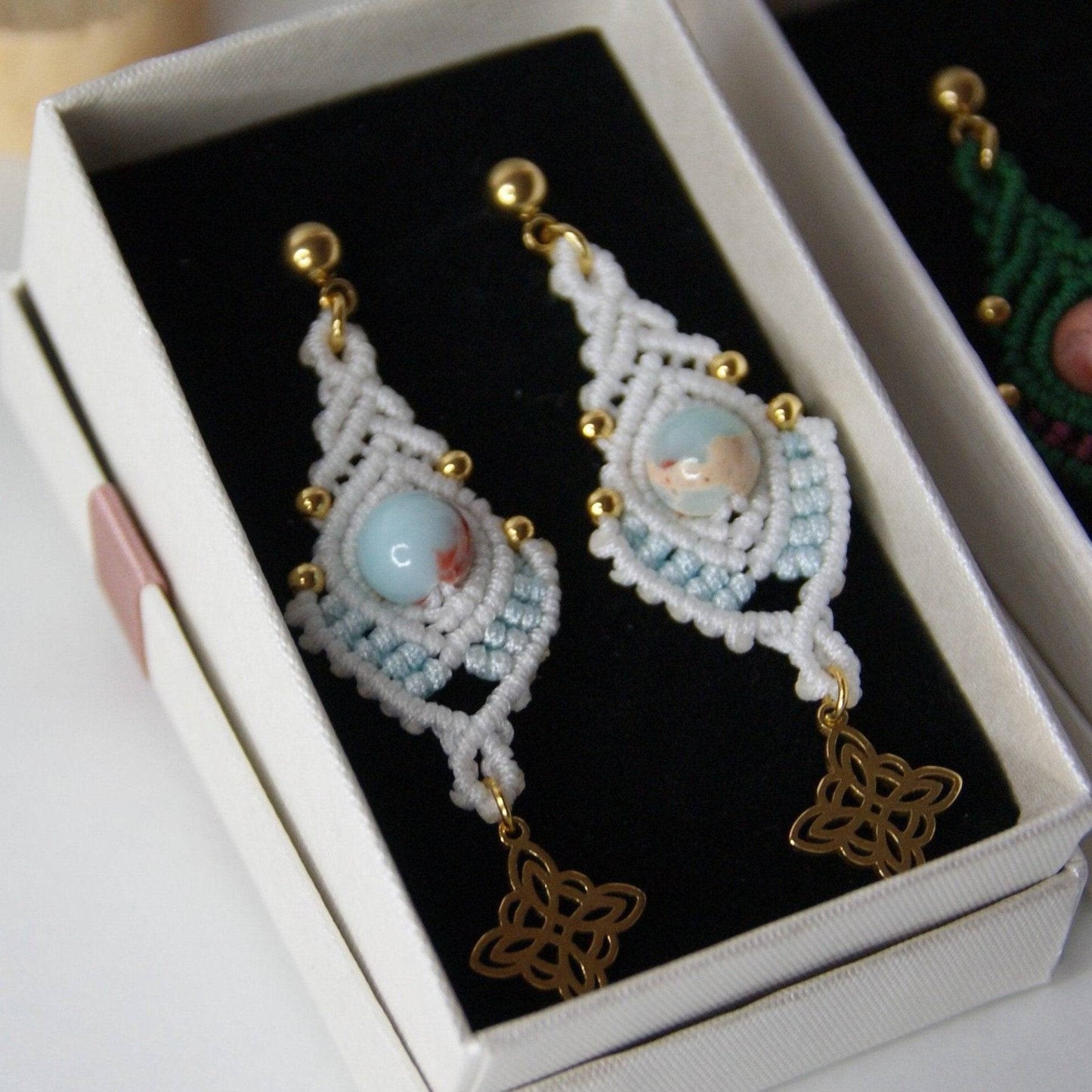 Descubre la fusión perfecta de artesanía y estilo con los pendientes Indian, diseñados para destacar y realzar cualquier atuendo. Estos pendientes, elaborados con hilo de nailon, piedras naturales y cuentas de acero inoxidable, combinan dos colores vibrantes en un diseño único y sofisticado.
