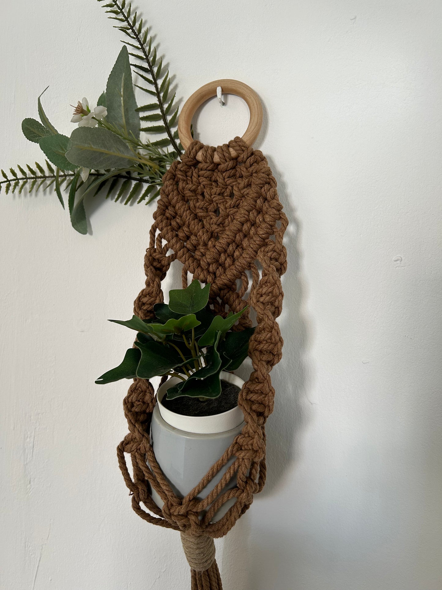 Transforma tu espacio con el Portamacetas Brown, una pieza única que combina la belleza natural con la artesanía moderna. Este portamacetas está meticulosamente diseñado utilizando la técnica de macramé sobre una base de madera en forma de aro, creando un accesorio elegante y funcional para tus plantas favoritas.