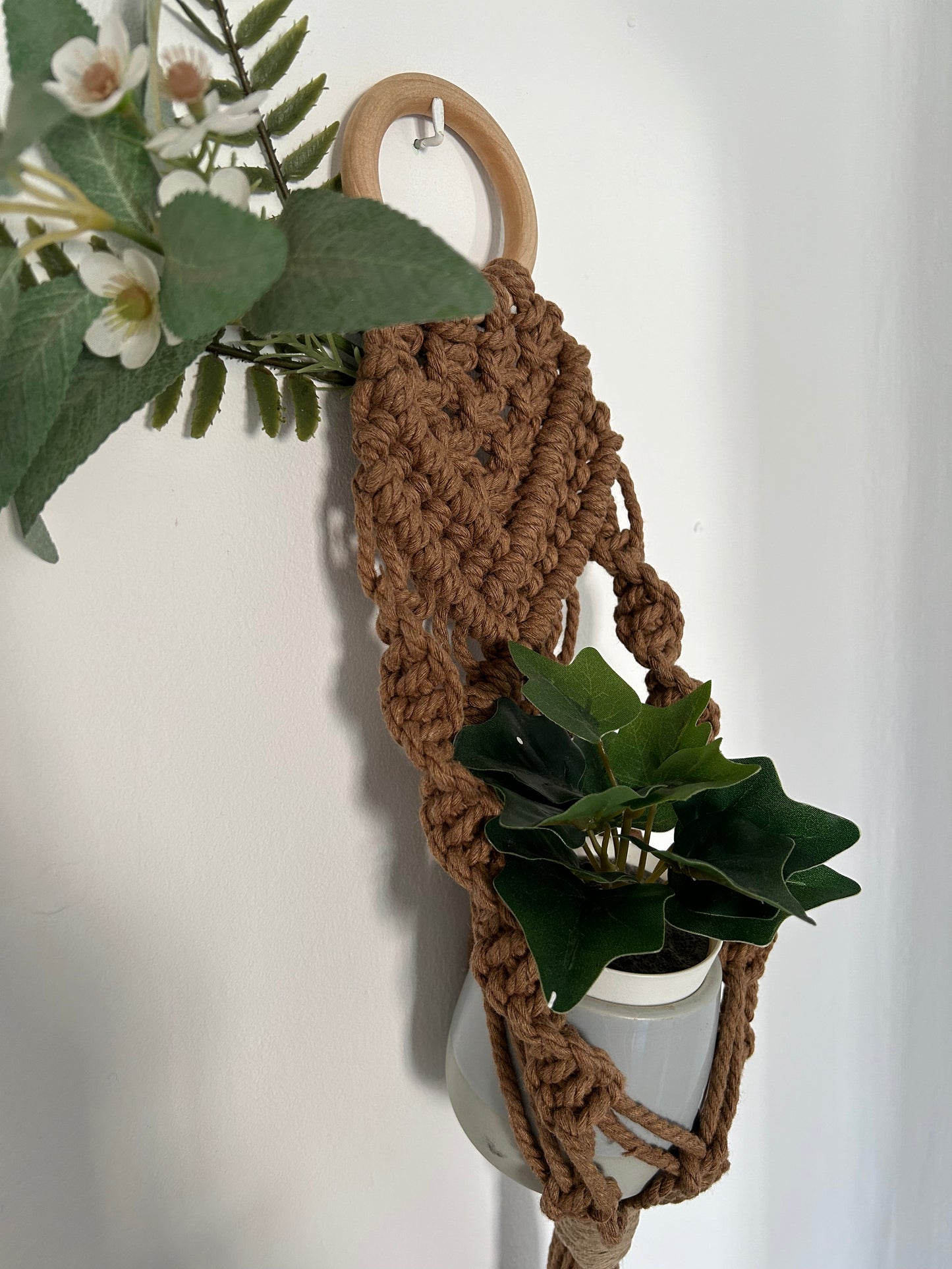 Transforma tu espacio con el Portamacetas Brown, una pieza única que combina la belleza natural con la artesanía moderna. Este portamacetas está meticulosamente diseñado utilizando la técnica de macramé sobre una base de madera en forma de aro, creando un accesorio elegante y funcional para tus plantas favoritas.
