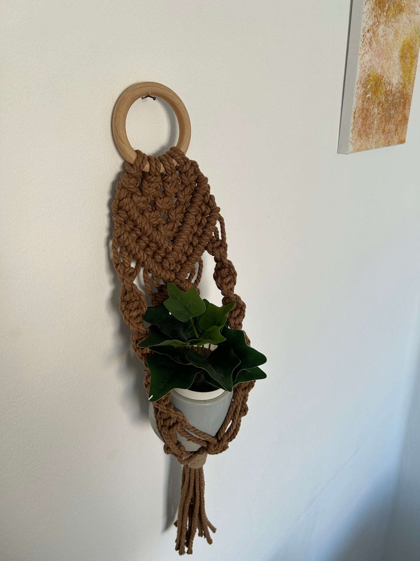 Transforma tu espacio con el Portamacetas Brown, una pieza única que combina la belleza natural con la artesanía moderna. Este portamacetas está meticulosamente diseñado utilizando la técnica de macramé sobre una base de madera en forma de aro, creando un accesorio elegante y funcional para tus plantas favoritas.