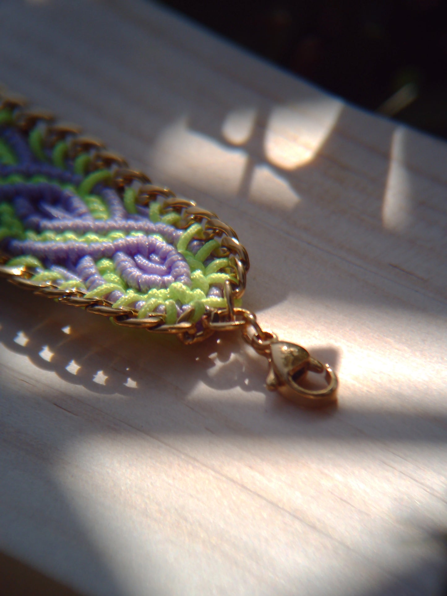 Brazalete de macramé hecho a mano con diseño geométrico, tonos vibrantes inspirados en el mar, joyería artesanal con cadena dorada