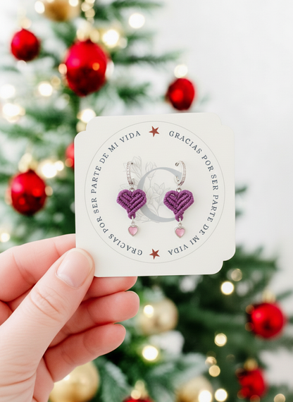 Mujer sosteniendo el adorno de Navidad, mostrando los pendientes de corazón artesanos.