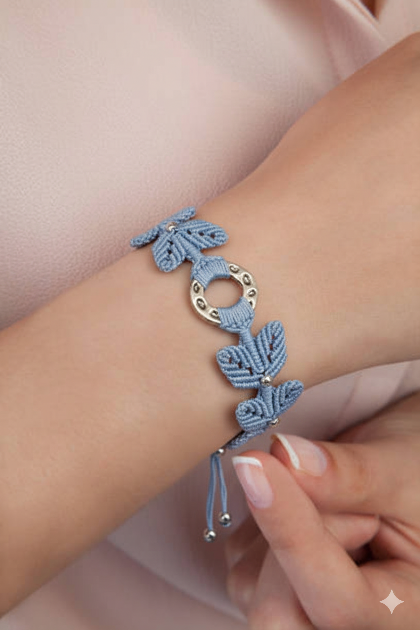 Brazalete artesanal de macramé en azul celeste con pieza central circular metálica y cierre ajustable.