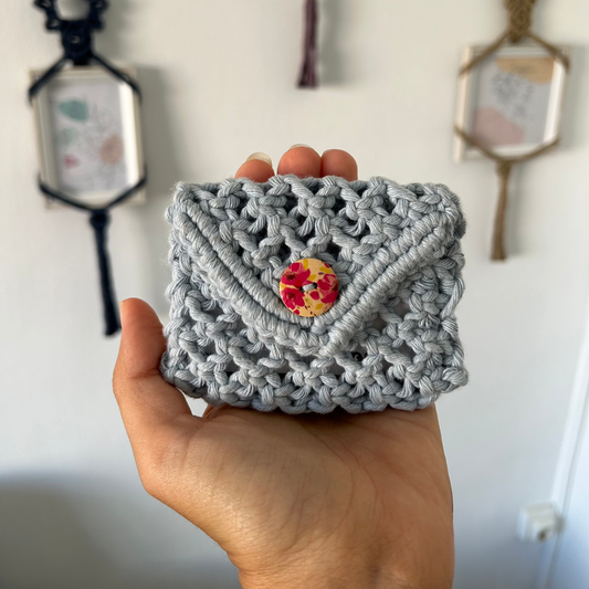Descubre el monedero Miranda, una pieza única y artesanal, elaborada con la técnica de macramé. Confeccionado con hilo de algodón de urdimbre de 2 mm, cada monedero requiere más de cinco horas de trabajo meticuloso, garantizando un acabado de calidad excepcional. Este accesorio no solo es práctico, sino que también aporta un toque de estilo y originalidad a tu día a día.