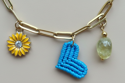 Collar dorado con charms variados en forma de corazón azul tejido, charms de acero. Tendencia 2026