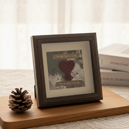 Mini marco de madera oscura con corazón de macramé color burdeos sobre fondo estampado y la frase "Miracles happen every day". Ideal para decoración artesanal.