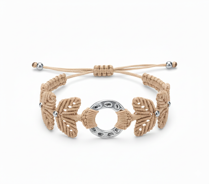 Brazalete artesanal de macramé en beige con pieza central circular metálica y cierre ajustable.