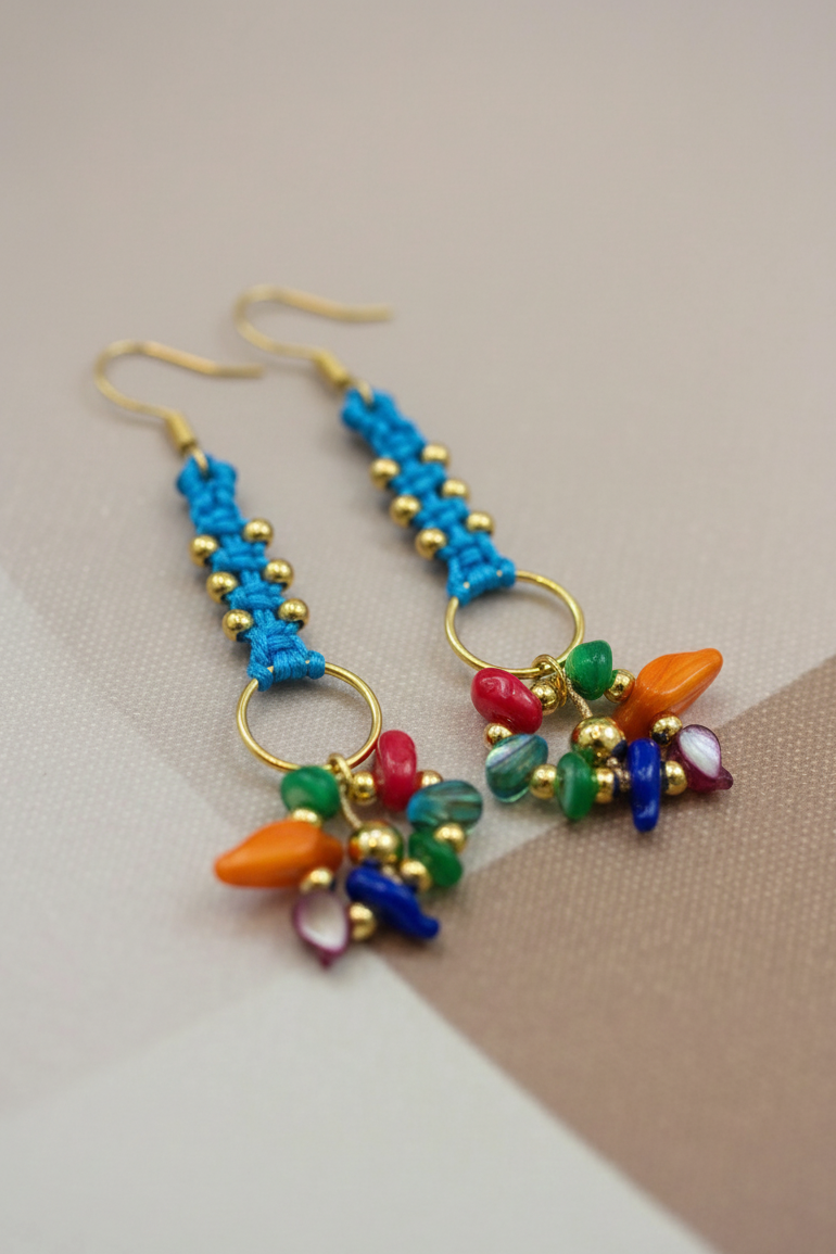 Pendientes artesanales Aura con tejido en hilo, cuentas doradas y racimo de pequeñas piedras naturales en la parte inferior, disponibles en varios colores.