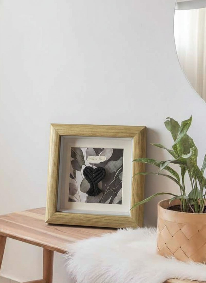 Mini marco de madera marrón con corazón de macramé negro, destacado sobre un fondo limpio y minimalista. Producto de regalo original.