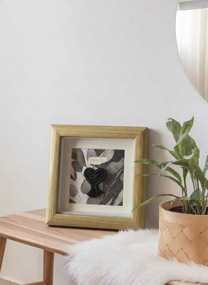 Mini marco de madera marrón con corazón de macramé negro, destacado sobre un fondo limpio y minimalista. Producto de regalo original.