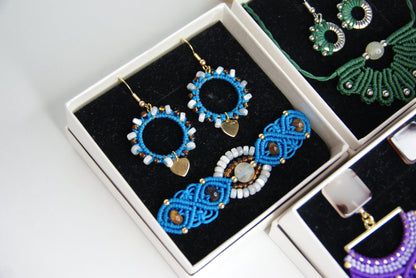 Sumérgete en el arte bohemio con el "Pack Maravilla", una colección excepcional de joyería hecha a mano en macramé. Estos exclusivos packs incluyen pendientes y pulsera o pendientes y collar, cada uno meticulosamente elaborado con técnicas tradicionales que destacan por su intrincado diseño y su belleza natural.