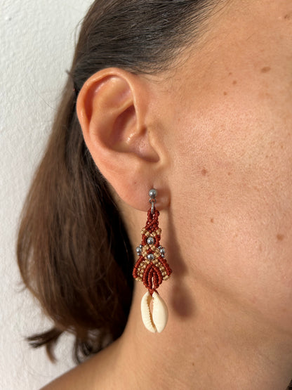 Sumérgete en la belleza del mar con los pendientes Ola Marina, una pieza única que captura la esencia de la costa. Estos pendientes están meticulosamente elaborados con hilo de nailon, conchas naturales y cuentas de acero inoxidable, utilizando la técnica de macramé para ofrecerte un accesorio sofisticado y lleno de estilo.
