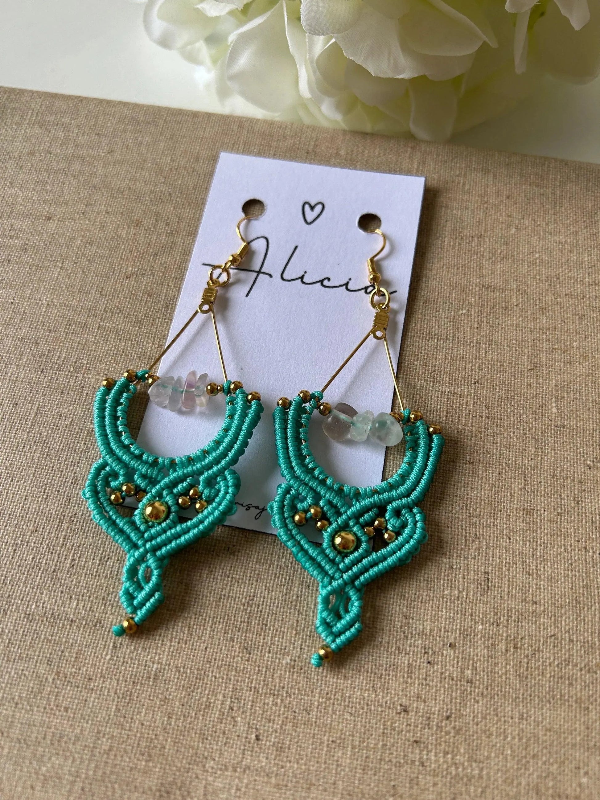 Añade un toque de frescura y sofisticación a tu estilo con los pendientes Cactus, una pieza exclusiva elaborada con la técnica de macramé. Confeccionados con hilo de nailon, cuentas de acero inoxidable y piedras naturales, estos pendientes combinan elegancia y diseño contemporáneo para un acabado único.