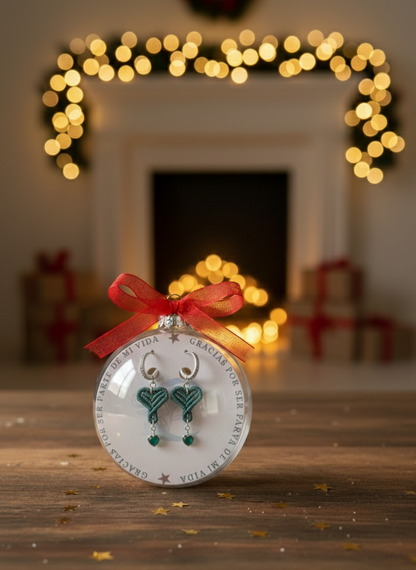 Primer plano del adorno navideño de esfera con lazo rojo, que contiene el set de pendientes de macramé hecho a mano.