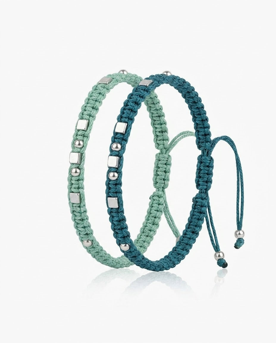 Set de dos pulseras de cordón trenzado a mano en verde menta y azul petróleo con cuentas metálicas, fondo blanco, foto de producto