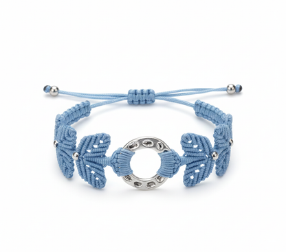 Brazalete artesanal de macramé en azul celeste con pieza central circular metálica y cierre ajustable.