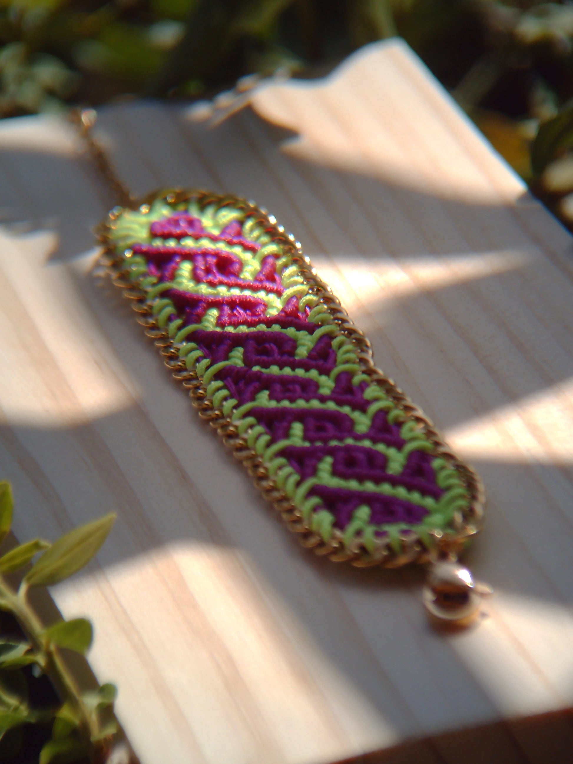 Brazalete de macramé hecho a mano con diseño geométrico, tonos vibrantes inspirados en el mar, joyería artesanal con cadena dorada