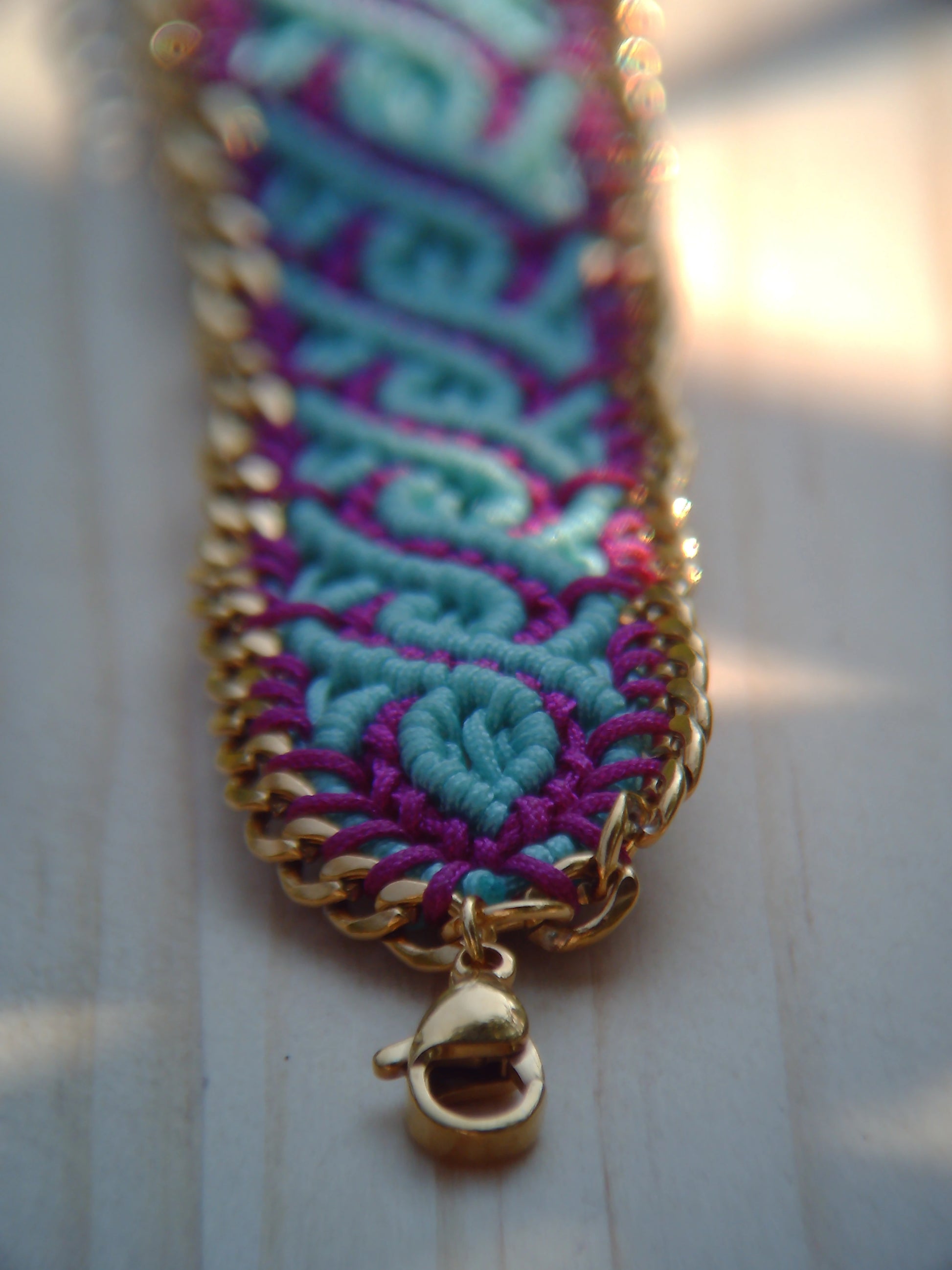 Brazalete de macramé hecho a mano con diseño geométrico, tonos vibrantes inspirados en el mar, joyería artesanal con cadena dorada