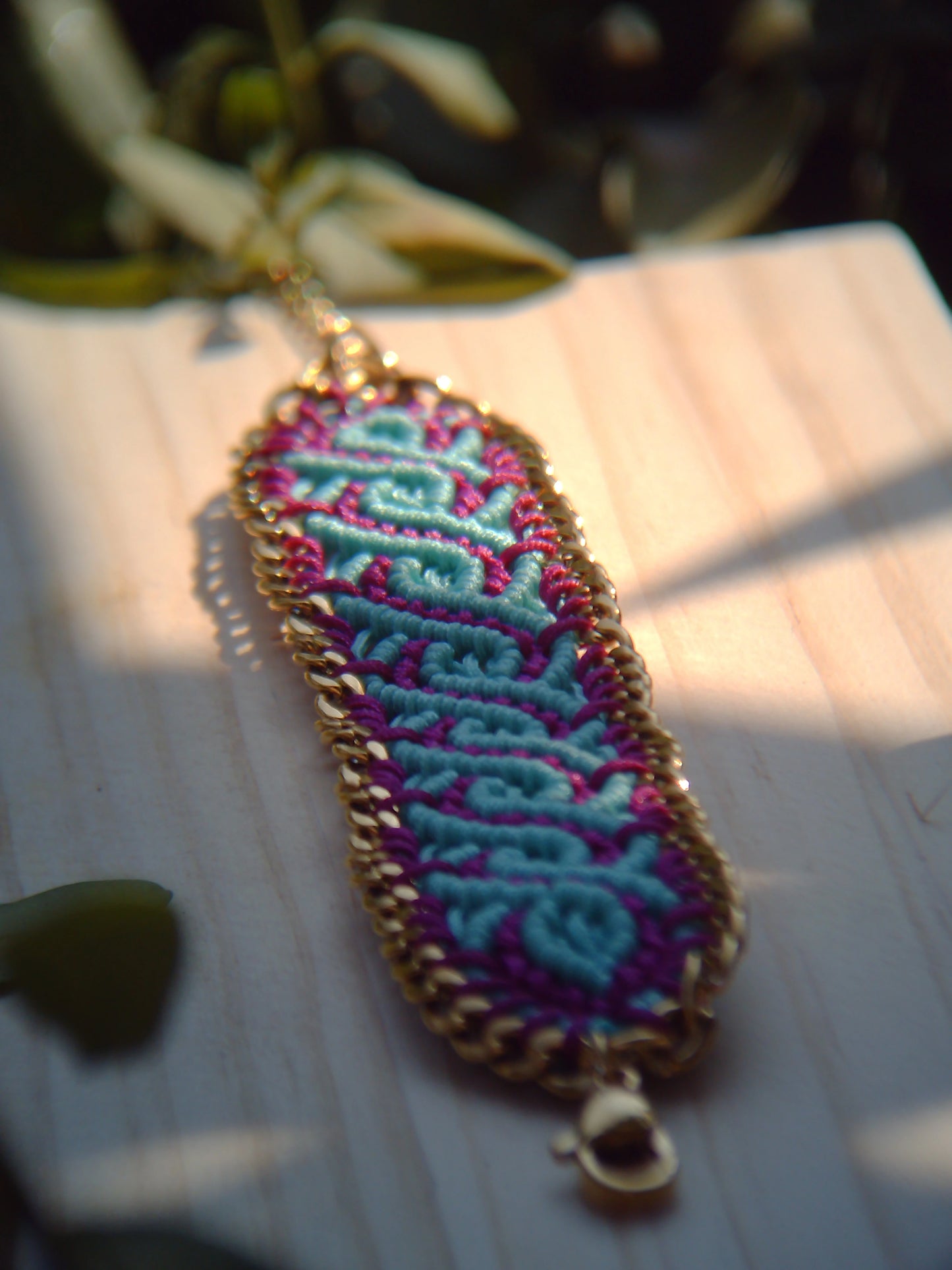 Brazalete de macramé hecho a mano con diseño geométrico, tonos vibrantes inspirados en el mar, joyería artesanal con cadena dorada