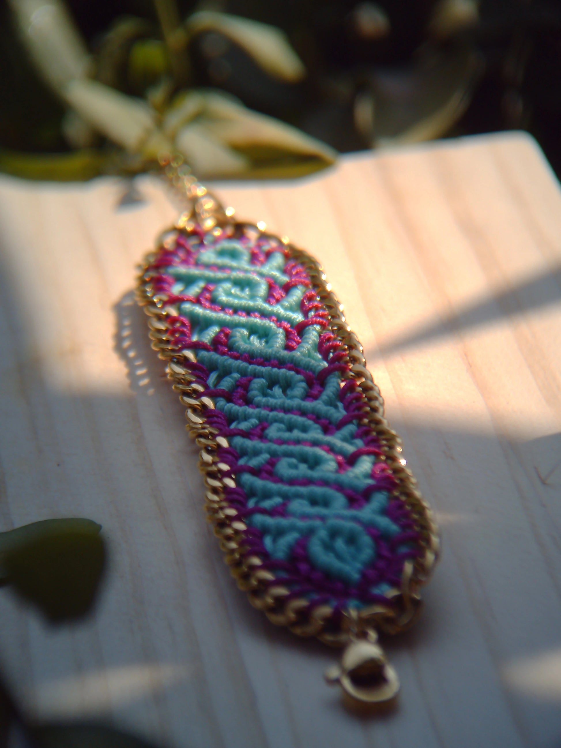 Brazalete de macramé hecho a mano con diseño geométrico, tonos vibrantes inspirados en el mar, joyería artesanal con cadena dorada