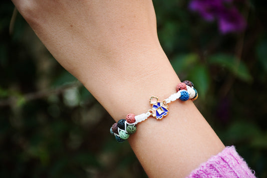 Pulsera Ofrenda ajustable con hilo de nailon, piedras volcánicas y charm de fallera en acero inoxidable, personalizable con inicial.